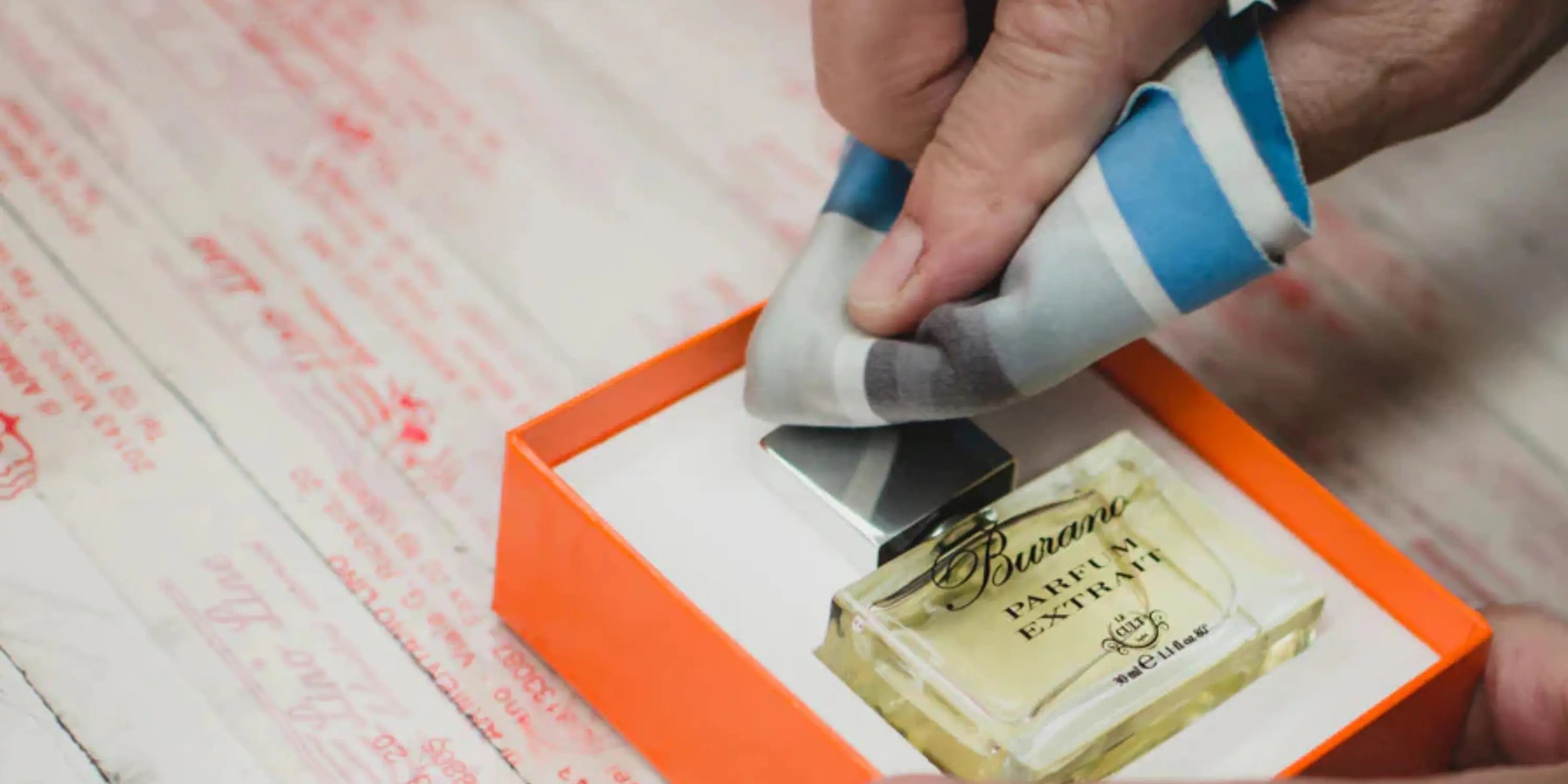 Curiamo ogni confezione Le Cult per il tuo profumo perfetto: qui una mano pulisce una ad una la bottiglietta da regalare o regalarsi